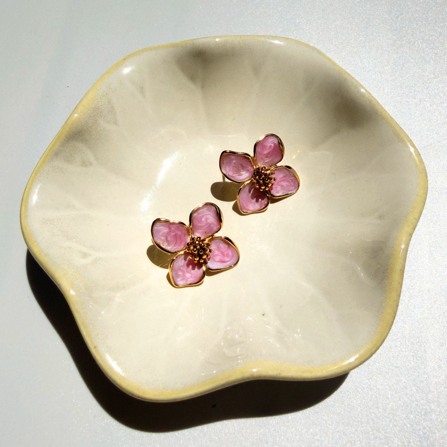 Floral earrings on a decorative ceramic dish against a light background