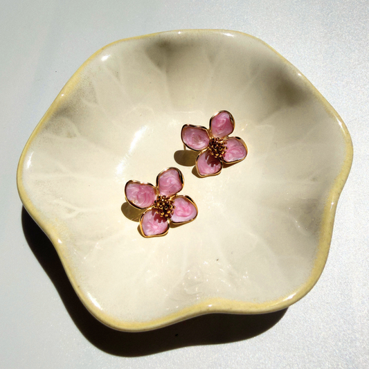 Floral earrings on a decorative ceramic dish against a light background